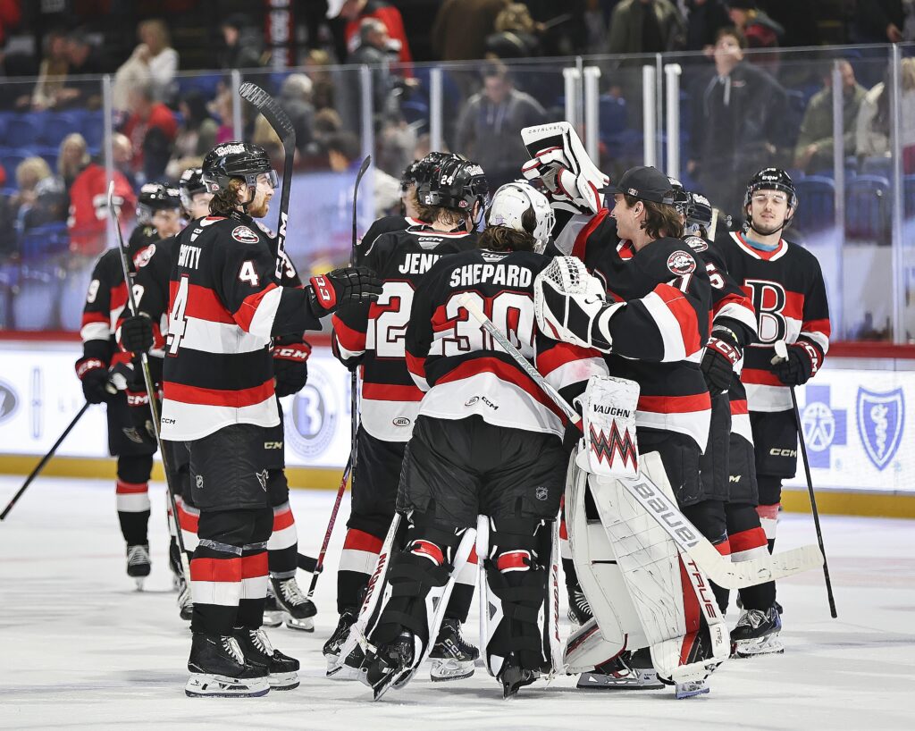 Hockey players celebrate a win with their goaltender.